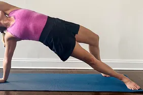 A person wearing the Athleta Crosscourt Skort performing a side plank on an exercise mat indoors