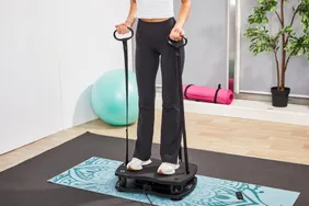 A person using a vibration plate in a workout setting with accessories