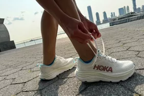 A person ties the laces on the HOKA Women's Gaviota 5 Running Shoes