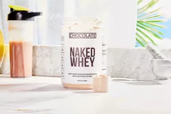 Naked Whey Chocolate Protein Powder displayed on a marble counter