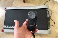 Hand holding controller for Egofit Walker Pro-M1 Treadmill with treadmill in background