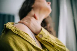 Person holding their neck depicting discomfort or pain in the neck area