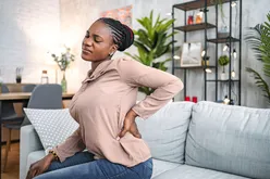 Person suffering with back pain while sitting at home