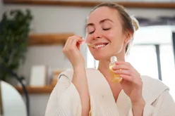 Person applying a serum using a dropper smiling and seeming content