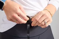 A person attaching the emergency cord of the WalkingPad X21 Double-Fold Treadmill to their pants