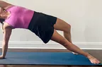 A person wearing the Athleta Crosscourt Skort performing a side plank on an exercise mat indoors